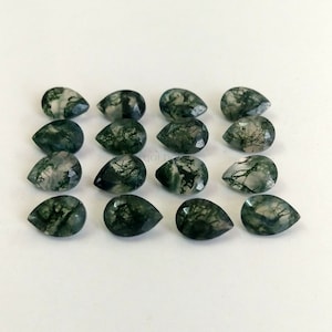 Könnte beinhalten: Eine Sammlung von 16 grünen Moosachat-Tropfensteinen. Die Steine sind durchscheinend und haben verschiedene grüne und weiße Muster.