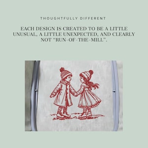 May include: A light-colored fabric held in a gray embroidery hoop featuring a red stitched design of two children in winter clothing holding hands. The text above reads: THOUGHTFULLY DIFFERENT. EACH DESIGN IS CREATED TO BE A LITTLE UNUSUAL, A LITTLE UNEXPECTED, AND CLEARLY NOT "RUN-OF-THE-MILL".