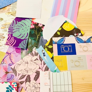 Peut inclure: Un assortiment de papiers d&eacute;coup&eacute;s aux motifs color&eacute;s, dont des fleurs, des feuilles tropicales, des papillons et un carnet de ch&egrave;ques. Les papiers d&eacute;coup&eacute;s sont dispos&eacute;s sur une surface en bois.