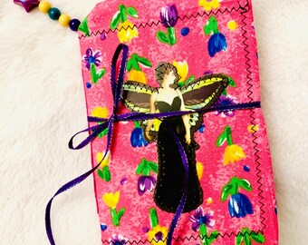 Peut inclure: Un journal fait à la main avec un motif floral rose. Le journal présente un ornement sur le thème du papillon et un ruban violet. Un charme de perles avec une étoile et des perles de bois est attaché au journal.
