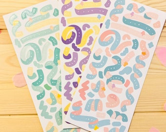 Op de afbeelding: Drie vellen met kleurrijke stickers met abstracte vormen en sterren. De stickers zijn in tinten groen, geel, paars, roze en blauw.