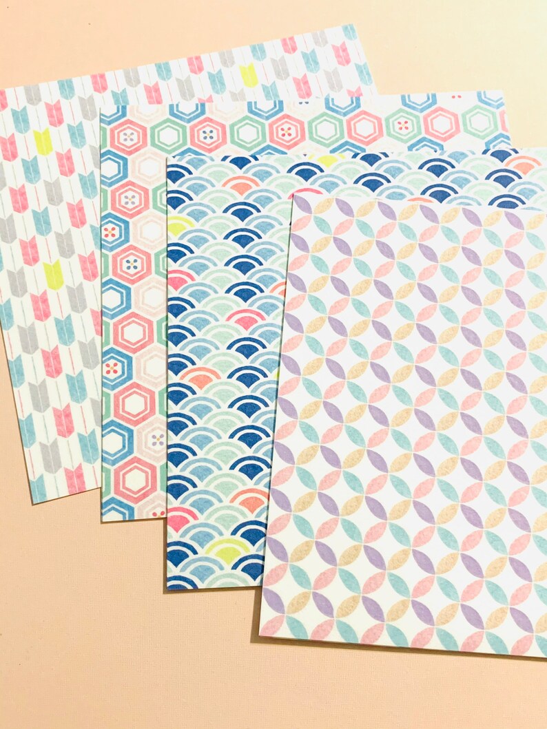 May include: A selection of patterned paper sheets featuring diverse designs. The patterns include arrows, hexagons, waves, and overlapping circles, in pastel shades such as pink, blue, yellow, and purple. The paper has a textured finish.