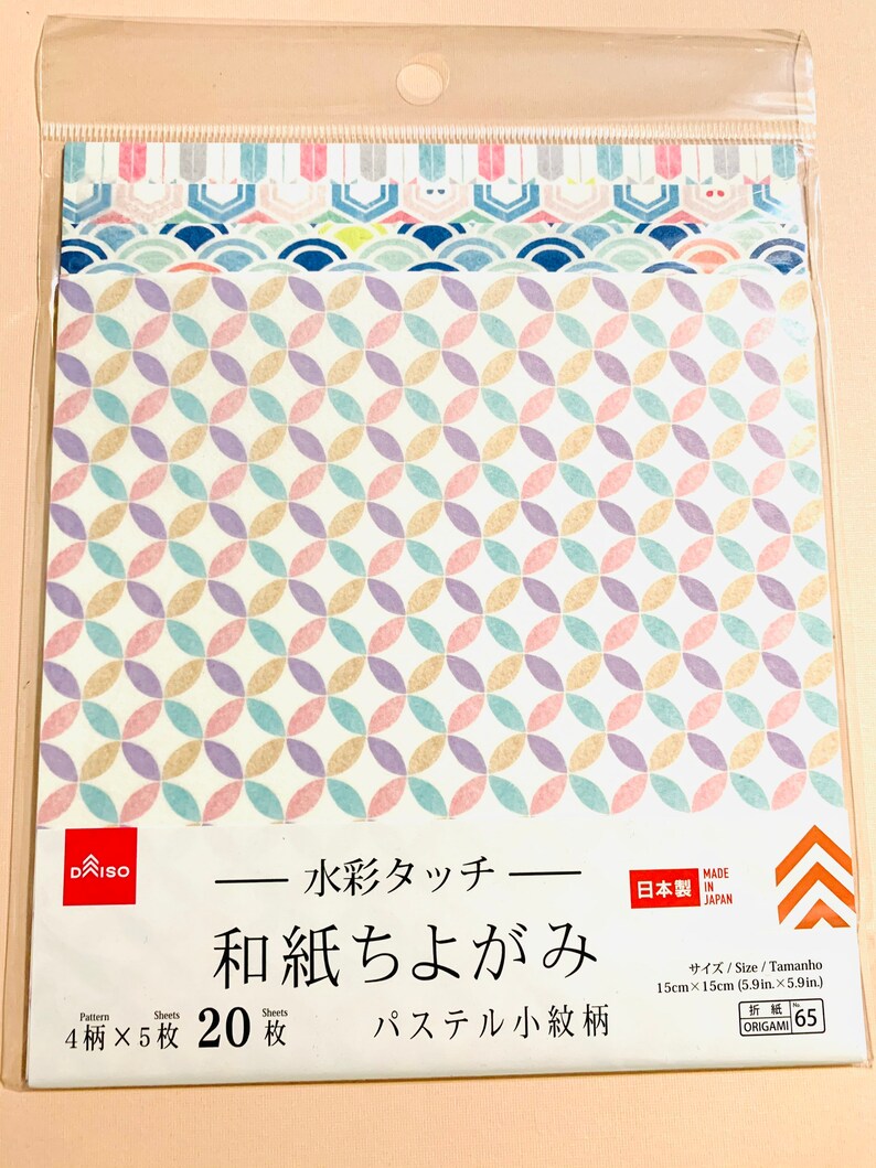 May include: A pack of origami paper featuring pastel geometric patterns. The pack contains 20 sheets, each 15cm x 15cm, with four different designs. Text on the packaging includes "DAISO", "Made in Japan", and Japanese characters.