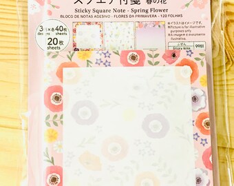 May include: A pack of square sticky notes titled Sticky Square Note - Spring Flower. The packaging features pink cherry blossoms and contains 120 sheets across 3 designs. The notes themselves have a white centre with a floral border of red, orange, yellow, and purple flowers on a pink background.