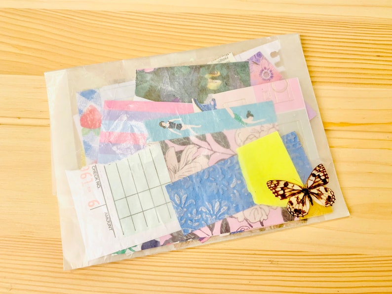 Peut inclure: Un sac en plastique transparent rempli de morceaux de papier color&eacute;s, dont une feuille &agrave; motifs avec le texte "Check No. 6", un post-it jaune et un autocollant de papillon.