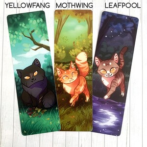 May include: Three bookmarks featuring illustrations of cats in different settings. The first bookmark features a black cat with yellow eyes in a green forest setting. The second bookmark features an orange and white cat in a forest setting with green and brown foliage. The third bookmark features a brown and white tabby cat in a dark blue forest setting with a crescent moon reflected in a pool of water.
