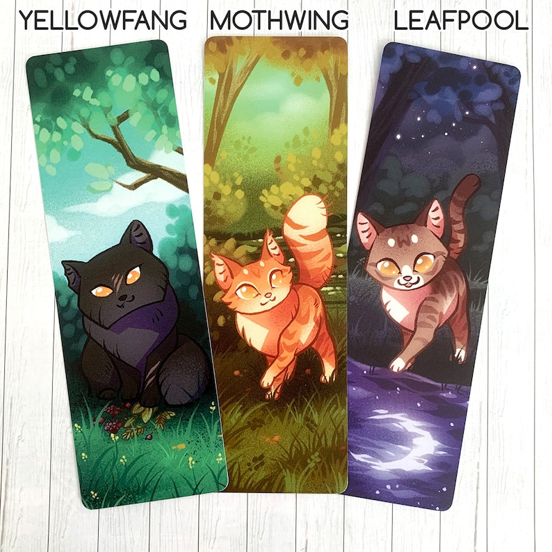 May include: Three bookmarks featuring illustrations of cats in different settings. The first bookmark features a black cat with yellow eyes in a green forest setting. The second bookmark features an orange and white cat in a forest setting with green and brown foliage. The third bookmark features a brown and white tabby cat in a dark blue forest setting with a crescent moon reflected in a pool of water.