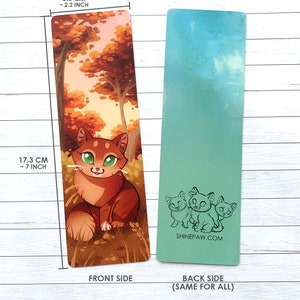 May include: A bookmark featuring a cartoon orange tabby cat sitting in a forest with fall foliage. The back side of the bookmark has a light blue background with three cartoon cats in black outline. The bookmark is 7 inches tall and 2.2 inches wide. The text "SHINEPAW.COM" is printed on the back of the bookmark.