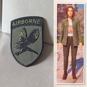 Könnte beinhalten: Ein olivgrüner Aufnäher mit dem Wort "AIRBORNE" oben. Darunter befindet sich ein schwarz-grünes, gesticktes Bild eines Vogels im Flug. Der Aufnäher ist schildförmig. Das Bild zeigt auch eine Person, die ein grünes Hemd und eine dunkle Hose trägt.