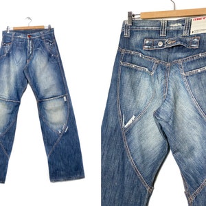 Puede incluir: Un par de pantalones vaqueros azules de mezclilla con detalles desgastados y un diseño único. Los pantalones tienen una etiqueta que dice "MET" en la parte posterior.