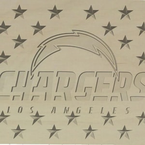 Puede incluir: Un letrero de madera con una imagen estilizada de un rayo y las palabras "Chargers Los Angeles" en negrita. El letrero está decorado con un patrón de estrellas.