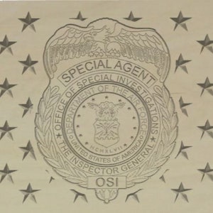 May include: A black and white image of a badge with the text "SPECIAL AGENT OFFICE OF SPECIAL INVESTIGATIONS DEPARTMENT OF THE AIR FORCE THE INSPECTOR GENERAL OSI" and a star design around the edge.