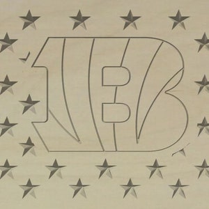 Puede incluir: Un letrero de madera con fondo marrón y un contorno blanco de la letra "B" con rayas. La letra está rodeada de un patrón de estrellas blancas.