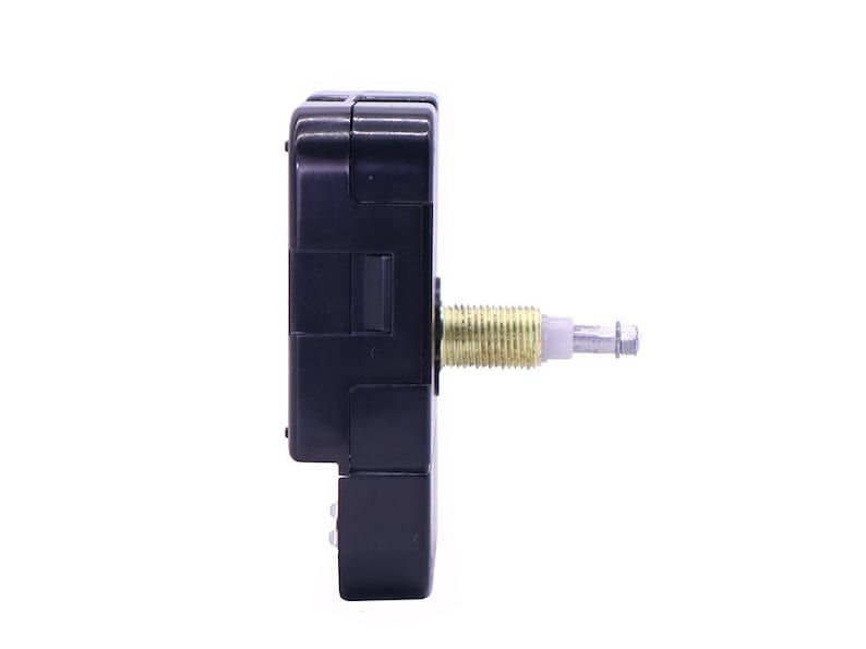 May include: A black clock movement with a gold-colored winding stem. The movement is designed for use in a clock.