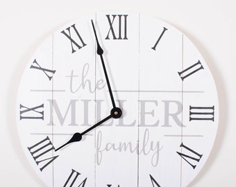 May include: White round clock with black Roman numeral hour markers and black hands. The clock face has the text "the MILLER family" in gray.