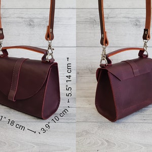 K&ouml;nnte beinhalten: Burgunderfarbene Leder-Umh&auml;ngetasche mit Tragegriff und verstellbarem Riemen. Die Tasche ist 18 cm lang, 10 cm breit und 14 cm hoch. Der Riemen ist hellbraun und wird mit silbernen Verschl&uuml;ssen befestigt. Die Tasche hat einen Klappverschluss mit Schnalle.