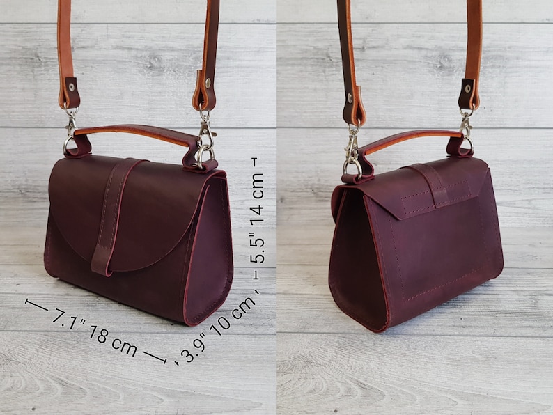 K&ouml;nnte beinhalten: Burgunderfarbene Leder-Umh&auml;ngetasche mit Tragegriff und verstellbarem Riemen. Die Tasche ist 18 cm lang, 10 cm breit und 14 cm hoch. Der Riemen ist hellbraun und wird mit silbernen Verschl&uuml;ssen befestigt. Die Tasche hat einen Klappverschluss mit Schnalle.