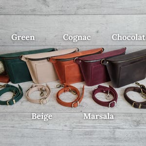 Puede incluir: Cinco ri&ntilde;oneras en colores verde, beige, co&ntilde;ac, marsala y chocolate, cada una con cremallera superior, un bolsillo frontal y una correa ajustable desmontable con herrajes met&aacute;licos. Las bolsas est&aacute;n etiquetadas como Green, Cognac, Chocolate, Beige, Marsala.