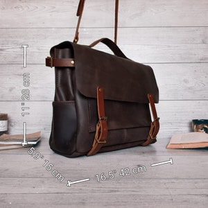 May include: A dark brown leather messenger bag with a top handle and adjustable shoulder strap. The bag features two front buckle straps and side pockets. Dimensions are 11 inches by 5.9 inches by 16.5 inches as indicated in the image.
