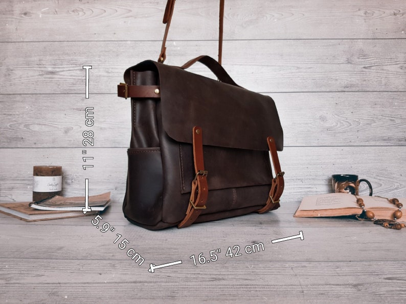 May include: A dark brown leather messenger bag with a top handle and adjustable shoulder strap. The bag features two front buckle straps and side pockets. Dimensions are 11 inches by 5.9 inches by 16.5 inches as indicated in the image.