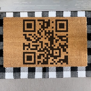 May include: A brown doormat with a black and white checkered border and a black QR code in the center.