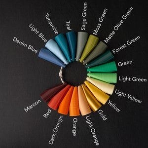 May include: A color chart with 18 different shades of paint, arranged in a circle. The colors include teal, turquoise, light blue, denim blue, maroon, red, dark orange, orange, sage green, moss green, matte olive green, forest green, green, light green, light yellow, yellow, gold, and light orange.
