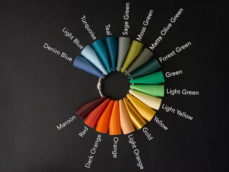 May include: A color chart with 18 different shades of paint, arranged in a circle. The colors include teal, turquoise, light blue, denim blue, maroon, red, dark orange, orange, sage green, moss green, matte olive green, forest green, green, light green, light yellow, yellow, gold, and light orange.