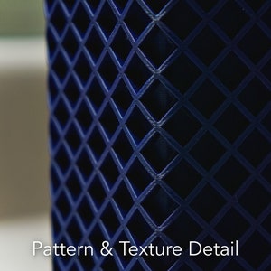 May include: A close-up of a dark blue object with a diamond-shaped pattern. The pattern is raised and creates a textured surface.