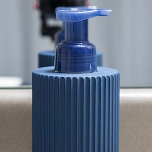 May include: A blue soap dispenser with a ribbed base and a blue pump top.