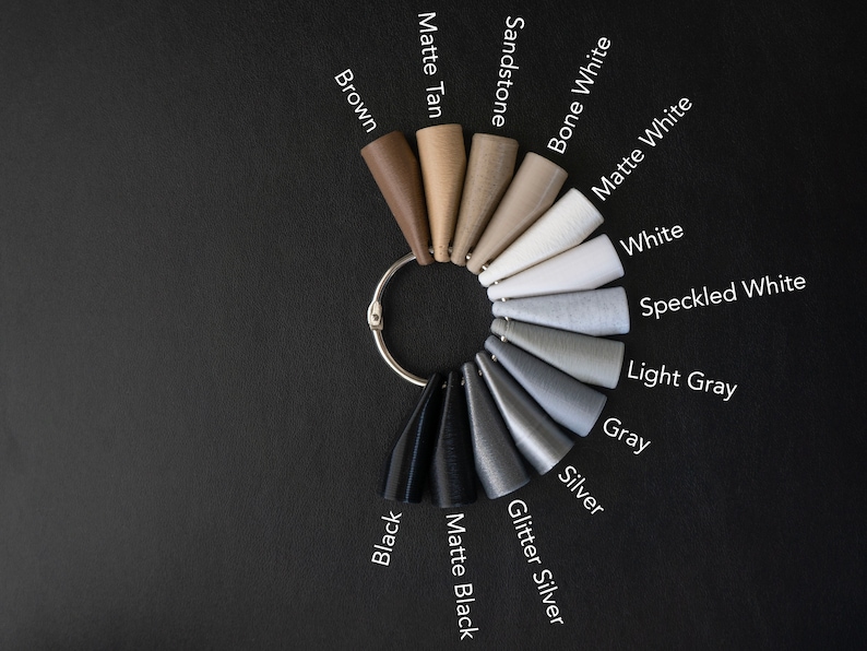 May include: A color chart with 14 different color swatches in the shape of cones. The colors are: Brown, Matte Tan, Sandstone, Bone White, Matte White, White, Speckled White, Light Gray, Gray, Silver, Glitter Silver, Matte Black, and Black.