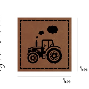 Könnte beinhalten: Ein braunes Lederpatch mit einer schwarzen Silhouette eines Traktors mit einer Rauchwolke darüber. Das Patch misst 4 cm x 4 cm.