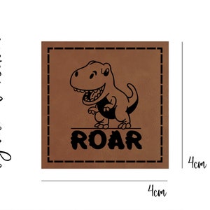 Könnte beinhalten: Ein braunes Lederpatch mit einem schwarzen Comic-Dinosaurier und dem aufgedruckten Wort "ROAR". Das Patch misst 4 cm x 4 cm.