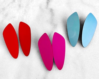 May include: A set of six earrings in three different colors: red, pink, and blue. The earrings are shaped like teardrops and have a glossy finish.