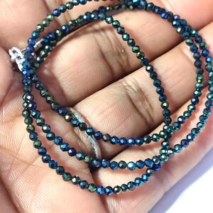 Puede incluir: Una hebra de cuentas facetadas de color azul oscuro con un brillo metálico. Las cuentas son pequeñas y de tamaño uniforme.