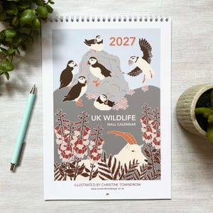 May include: A 2027 wall calendar titled UK WILDLIFE featuring illustrations of puffins on a rocky outcrop and a goat among foxglove flowers. The cover includes the text 2027, UK WILDLIFE WALL CALENDAR, and ILLUSTRATED BY CHRISTINE TOWNDROW.