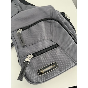 May include: Gray Swissgear shoulder bag with multiple zippered compartments. The bag has a textured fabric and features the Swissgear logo on a black and silver label. The zippers have silver pulls with black fabric tabs.
