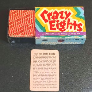 May include: Vintage Crazy Eights card game box with a red and white patterned card deck. The box is colorful with the game title in red and yellow. A rules card is in front of the box.