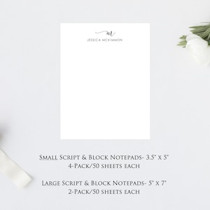 May include: A white notepad with the text "JESSICA MCKIMMON" and a handwritten "M" at the top. The notepad is on a white surface. Below the notepad is text that reads "SMALL SCRIPT & BLOCK NOTEPADS- 3.5" x 5" 4-PACK/50 SHEETS EACH" and "LARGE SCRIPT & BLOCK NOTEPADS- 5" x 7" 2-PACK/50 SHEETS EACH".