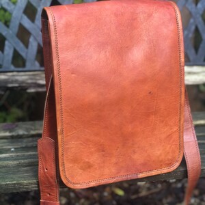 May include: A brown leather messenger bag with a flap closure and adjustable strap. The bag has a worn, vintage look.