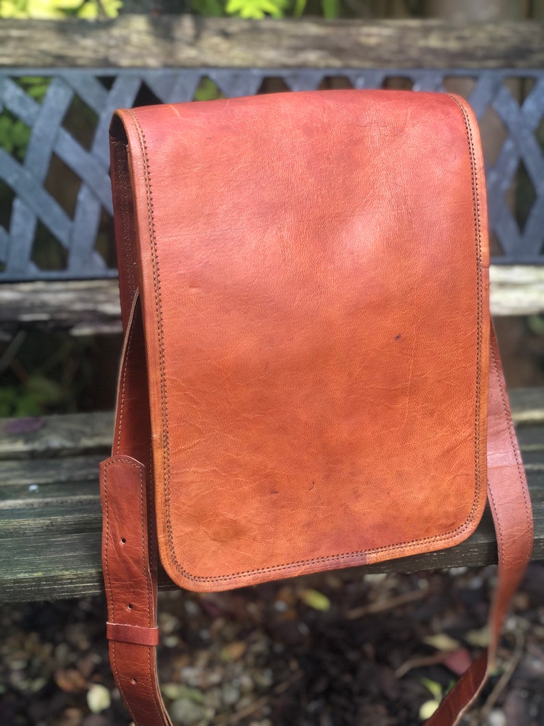 May include: A brown leather messenger bag with a flap closure and adjustable strap. The bag has a worn, vintage look.
