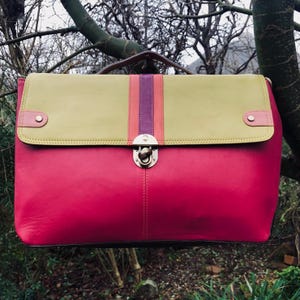 May include: A pink and green leather briefcase with a metal clasp and a purple and orange stripe.