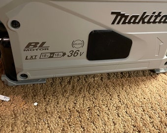 May include: A gray Makita power tool with a black brake lever. The tool has a black label that reads "BL Motor LXT 18v + 18v 36v".