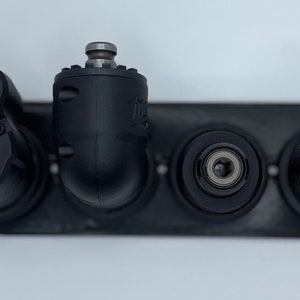 Puede incluir: Cuatro brocas de taladro negras con diferentes accesorios, incluyendo un accesorio de &aacute;ngulo recto, un accesorio recto y un accesorio de portabrocas. Las brocas de taladro est&aacute;n montadas en un bastidor de metal negro.