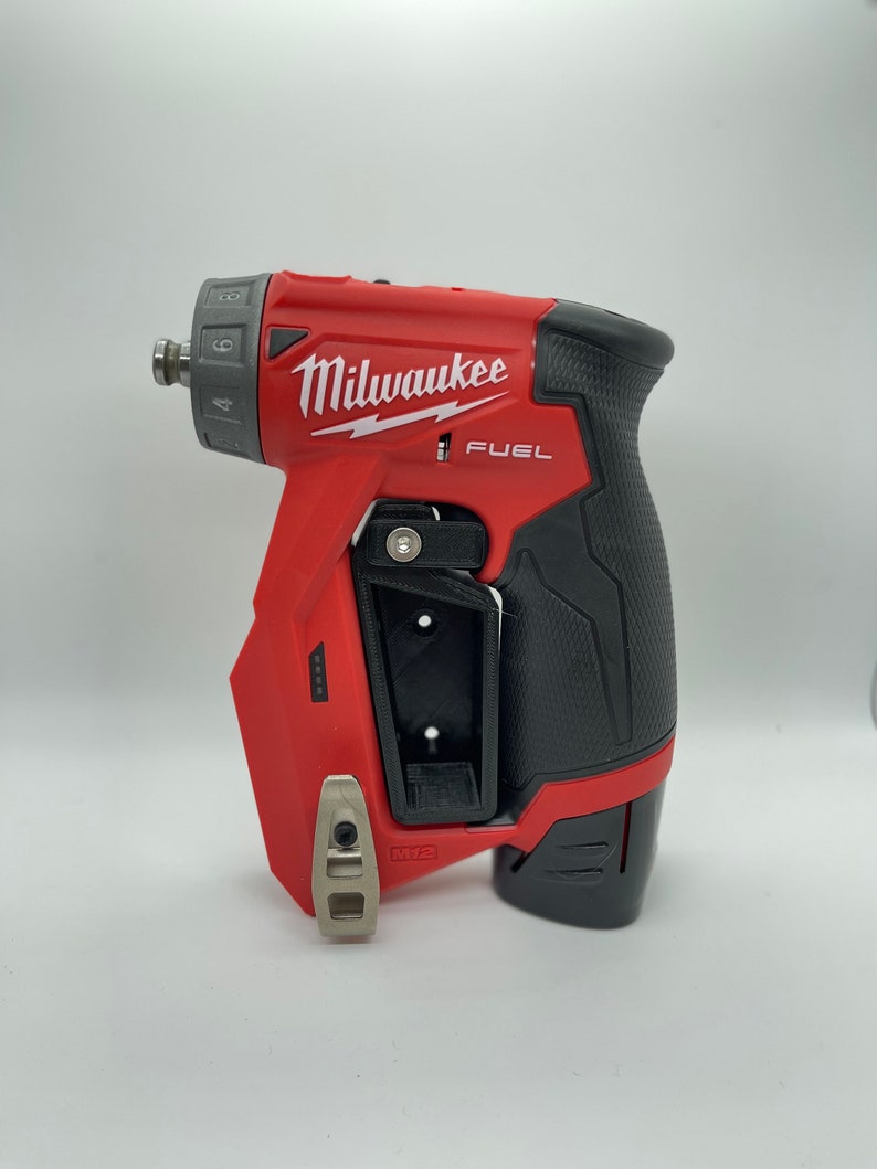 Puede incluir: Un taladro atornillador inal&aacute;mbrico Milwaukee FUEL 12V rojo y negro con un clip de cintur&oacute;n y un dial de velocidad variable. El taladro tiene un agarre de goma negro y un portabrocas de metal plateado.