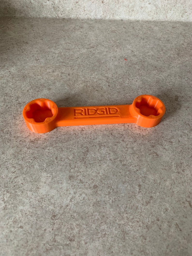 Puede incluir: Una llave de pl&aacute;stico naranja con la palabra "RIDGID" impresa en ella. La llave tiene dos extremos, cada uno con una abertura de tama&ntilde;o diferente.