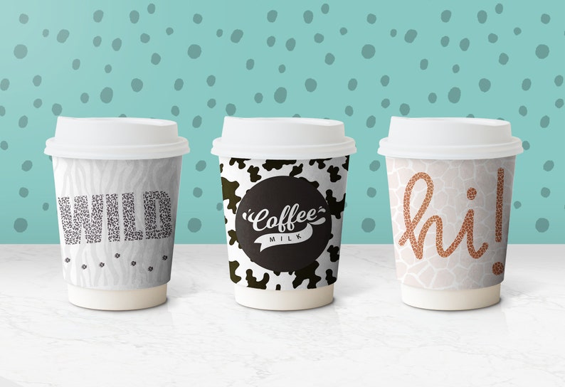 May include: Three disposable coffee cups with different animal print designs. The first cup has a zebra print with the word "WILD" in black text. The second cup has a cow print with the words "Coffee Milk" in black text. The third cup has a giraffe print with the word "hi!" in orange text.