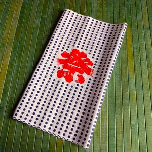 May include: White fabric with a navy blue polka dot pattern and a red Japanese character in the centre.