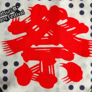 May include: A white fabric with a blue polka dot pattern. A red Japanese kanji character is centred on the fabric. The text "Matsuri 祭" means Festival.