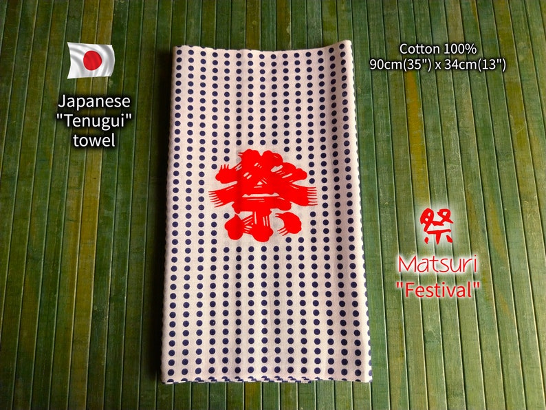 May include: A white cotton Japanese "Tenugui" towel with a blue polka dot pattern. The towel features a red Japanese character in the centre and the text "Matsuri" which means "Festival". The towel measures 90cm by 34cm.