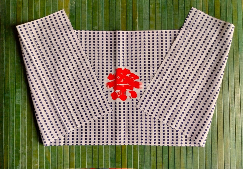 May include: White wrapping paper with a blue polka dot pattern. The paper is folded in half and has a red Chinese character in the centre.